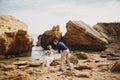 Outdoor beach wedding ceremony near the ocean, romantic happy couple sitting on stones at the beach