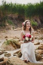 Outdoor beach wedding ceremony, stylish happy smiling bride sitting on stones and laughing