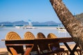 Outdoor cafe on the beach. Empty table and chairs on seashore. Outdoor tropical restaurant with boats and isles on background. Royalty Free Stock Photo