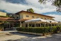 Outdoor cafe restaurant facade exterior design with patio food space under umbrellas surrounded green bushes