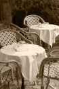 Outdoor cafe and restaurant with tables, chairs and glasses waiting for customers to arrive in black and white sepia tone