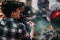 Outdoor camping scene with friends grilling sausages over a campfire Royalty Free Stock Photo