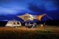 Outdoor camping tent in the forest park, party dinner with friends under tarp or flysheet and warm lighting at night near natural