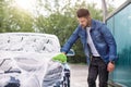 Outdoor car wash concept. Portrait of young man in casual wear, washing his luxury modern car in a self-service car wash Royalty Free Stock Photo