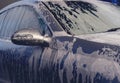 Car wash with soap. Fragment of gray vehicle with active foam. Sunny lighting.