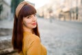 Outdoor city close up portrait of beautiful red haired young woman wearing yellow dress and knitted beige hoop on head Royalty Free Stock Photo