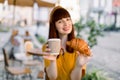 Outdoor city lifestyle portrait of young attractive Caucasian businesswoman, sitting at cafe with paper takeaway cup of Royalty Free Stock Photo