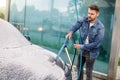 Outdoor cleaning of the car with soap foam using high pressure jet. Handsome bearded young man washing his electric car Royalty Free Stock Photo