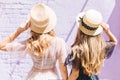 Outdoor close-up portrait from back of fair-haired curly sisters spending time together in sunny morning. Two slim Royalty Free Stock Photo