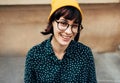 Outdoor close-up portrait of beautiful young woman smiling broadly wearing green shirt with white dots, transparent eyeglasse and