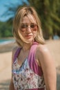 Young asian blonde woman wearing sunglasses, beach dress top, posing on sand, at sunset. Royalty Free Stock Photo