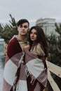 Outdoor close up portrait of young beautiful happy smiling couple bundled up in tartan blanket. Christmas, new year Royalty Free Stock Photo