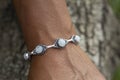 closeup of a hand wrist wearing silver metal bracelet with moon stone gem