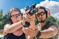 Outdoor closeup shot of focused caucasian skinny woman in protective headphones and glasses aiming at the target