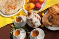 An outdoor composition with tea cups, a tea pot, a plate of pancakes, pastry, ripe fruit and field flowers on a bright table cloth Royalty Free Stock Photo