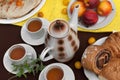 An outdoor composition with tea cups, a tea pot, a plate of pancakes, pastry, ripe fruit and field flowers on a bright table cloth Royalty Free Stock Photo