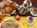 An outdoor composition with tea cups, a tea pot, a plate of pancakes, pastry, ripe fruit and field flowers on a bright table cloth Royalty Free Stock Photo