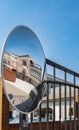 Outdoor convex safety mirror hanging on wall with reflection. Round mirror on a post to help cornering transport
