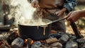 Outdoor cooking over campfire with steaming pot and hands stirring ingredients Royalty Free Stock Photo