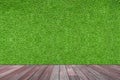 Empty space of Green artificial grass wall with wooden floor.