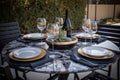 outdoor dining table set for four with wine glasses, plates, and silverware Royalty Free Stock Photo