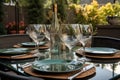 outdoor dining table set for four with wine glasses, plates, and silverware Royalty Free Stock Photo