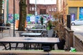 A outdoor dinning area on the street with a brown wooden wall around the tables and chairs colorful wall murals