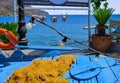 Outdoor display, traditional fisherman boat, fishing net, sun-dried octopuses on rope, blue sea and typical Greek hills