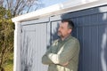 Outdoor dreaming handsome man middle aged thinking in home garage door in house garden Royalty Free Stock Photo