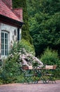 Outdoor eating area next to romantic cozy stone cottage with flowers in bloom Royalty Free Stock Photo