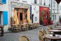 Outdoor empty cafe with tables arranged along a sidewalk in front of multiple buildings Royalty Free Stock Photo