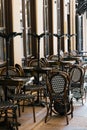 Outdoor empty closed coffee and restaurant terrace with tables, vintage white and black chairs. Cafe terrace on the