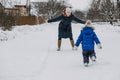 Outdoor family activities for happy winter holidays. Happy mother and two sons playing snowballs on snowy street in Royalty Free Stock Photo