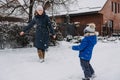 Outdoor family activities for happy winter holidays. Happy mother and two sons playing snowballs on snowy street in Royalty Free Stock Photo