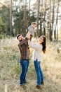 Outdoor family portrait of happy young parents, wearing stylish casual clothes, having fun and lifting up their little Royalty Free Stock Photo