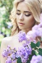 Outdoor fashion beautiful young woman surrounded by lilac flowers summer. Spring blossom lilac bush. Portrait of a girl blond Royalty Free Stock Photo