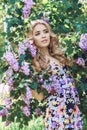 Outdoor fashion beautiful young woman surrounded by lilac flowers summer. Spring blossom lilac bush. Portrait of a girl blond Royalty Free Stock Photo