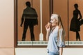 Outdoor fashion lifestyle portrait of young trendy girl eating ice cream in summer hot sunny day in street city Royalty Free Stock Photo