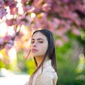 Outdoor fashion photo of beautiful young woman surrounded by flowers. Spring blossom Cherry blossom. Royalty Free Stock Photo