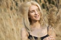 Outdoor fashion photo of young beautiful lady in autumn landscape with dry flowers Royalty Free Stock Photo