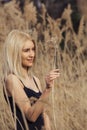 Outdoor fashion photo of young beautiful lady in autumn landscape with dry flowers. Royalty Free Stock Photo