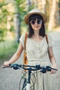 Outdoor portrait of attractive young brunette in a hat on a bicycle. Royalty Free Stock Photo