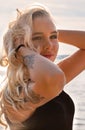 Outdoor fashion portrait of beautiful blonde lady at beach with flash tattoo