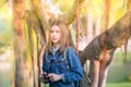 Outdoor fashion portrait traveler of stylish photographer girl holding camera, wearing jeans jacket, trendy sunglasses and backpac Royalty Free Stock Photo