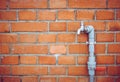 Outdoor faucet water tap with gray PVC pipe and red valve on red brick wall background texture, water saving concept Royalty Free Stock Photo