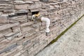 Outdoor faucet water tap with white PVC pipe and reed valve on light brick wall background texture Royalty Free Stock Photo
