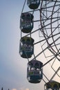 a ferris wheel with three colored seats with the sky in the background