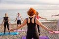 Outdoor fitness and yoga. Group of adult athletic Caucasian women are training on beach. Back view of trainer. Concept Royalty Free Stock Photo