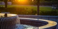 Outdoor fountain with reflective water at sunset