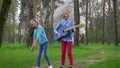 Outdoor games of childrens, cheerful girlfriends jointly jump with guitar in hand into the park in springtime